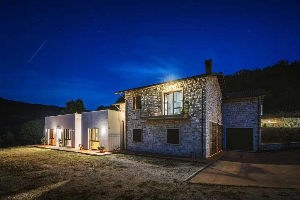 Esterno del casale in pietra illuminato di notte sotto il cielo stellato